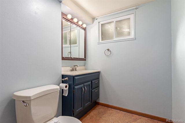 half bath featuring vanity, toilet, and baseboards