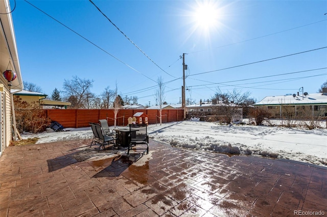 yard covered in snow featuring outdoor dining space, a patio area, and a fenced backyard