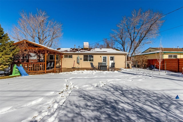 snow covered rear of property featuring fence