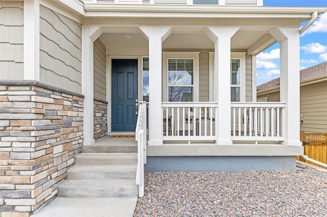 doorway to property featuring covered porch and stone siding
