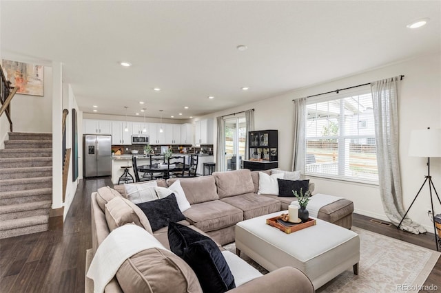 living room featuring dark wood-type flooring, recessed lighting, stairs, and baseboards