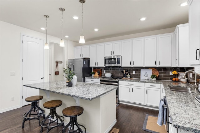 kitchen featuring a center island, dark wood finished floors, a sink, white cabinets, and stainless steel appliances