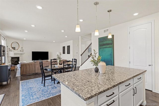 kitchen featuring visible vents, pendant lighting, light stone countertops, dark wood-type flooring, and white cabinetry