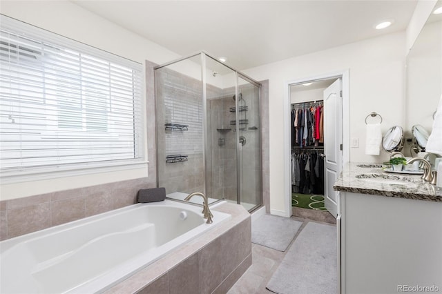 bathroom with tile patterned flooring, vanity, a shower stall, a spacious closet, and a bath