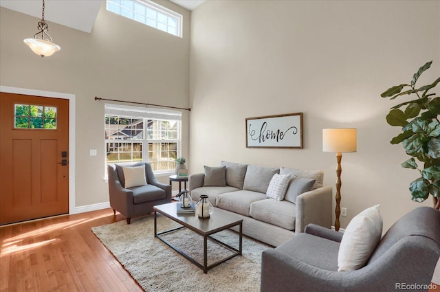 living room featuring light wood-type flooring and a towering ceiling