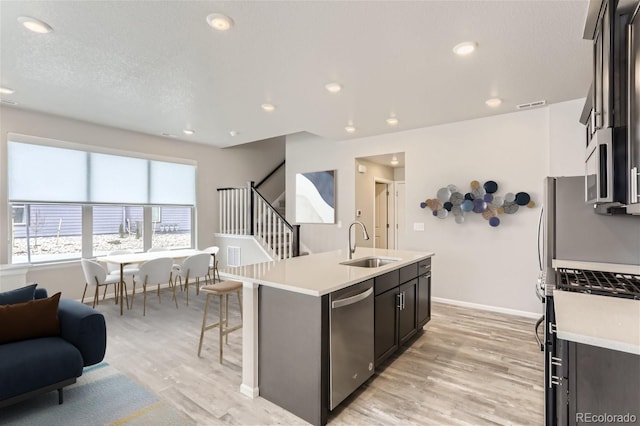 9457 W 58th Ln Unit A, Arvada, CO 80002 - kitchen with appliances with stainless steel finishes, open floor plan, light countertops, a center island with sink, and light wood-style floors