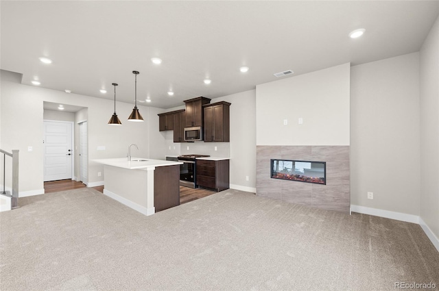 9457 W 58th Ln Unit A, Arvada, CO 80002 - kitchen with stainless steel appliances, carpet, dark brown cabinetry, a kitchen island with sink, and a tiled fireplace