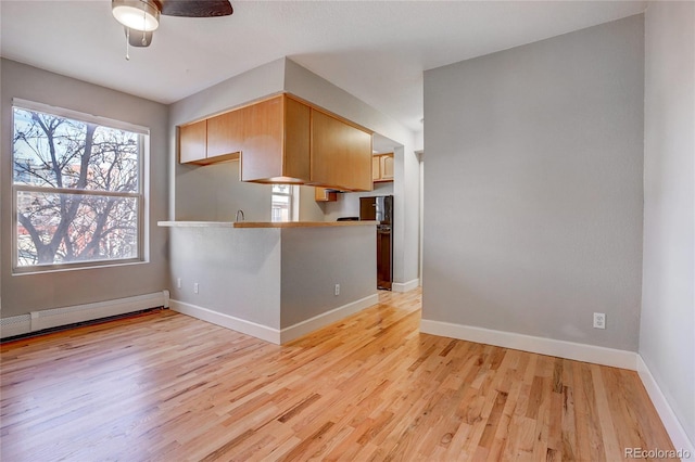 interior space with ceiling fan, a baseboard heating unit, light brown cabinetry, kitchen peninsula, and light wood-type flooring