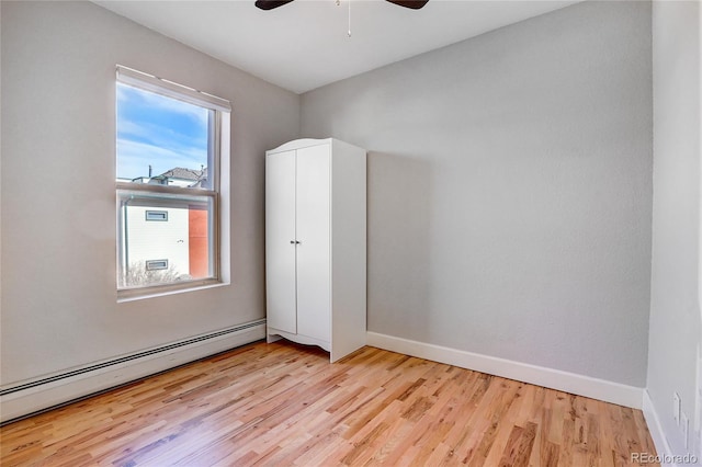 unfurnished bedroom featuring a baseboard radiator, ceiling fan, and light wood-type flooring