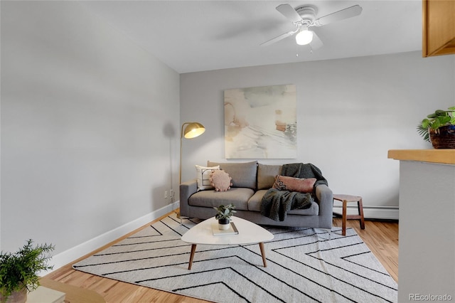 living room with ceiling fan, a baseboard heating unit, and light hardwood / wood-style floors