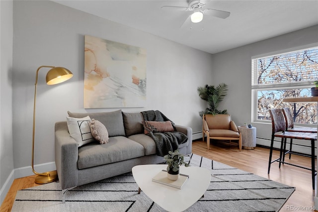 living room featuring a baseboard radiator, ceiling fan, and light wood-type flooring