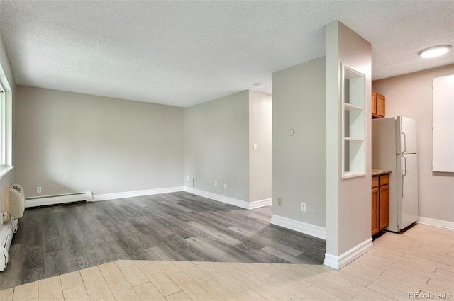 unfurnished room with a baseboard heating unit, light hardwood / wood-style flooring, and a textured ceiling