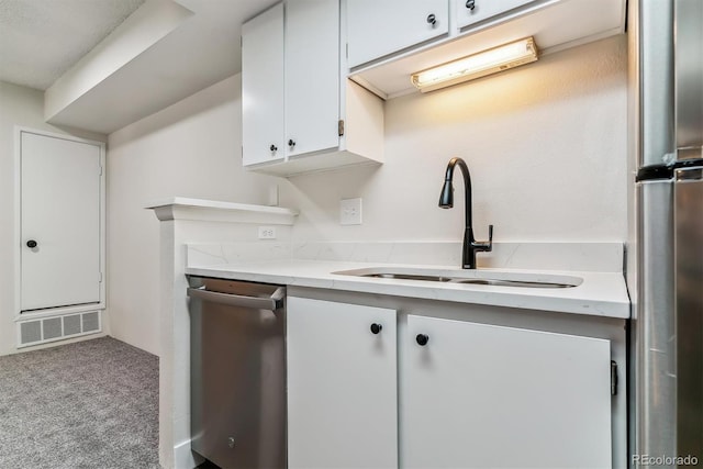 kitchen featuring dishwasher, sink, white cabinets, and light colored carpet