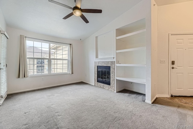 unfurnished living room with a tile fireplace, lofted ceiling, light colored carpet, and ceiling fan