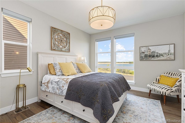 bedroom with a water view and dark wood-type flooring