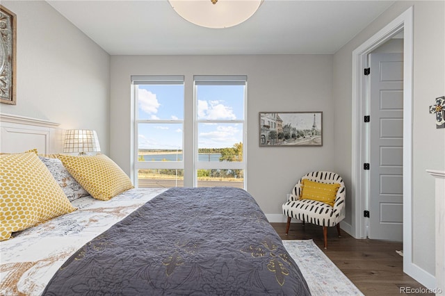 bedroom featuring a water view and dark hardwood / wood-style floors