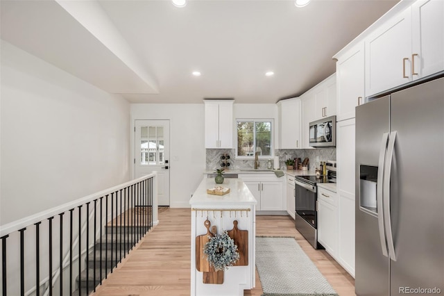 1948 S Zenobia St, Denver, CO 80219 - kitchen featuring stainless steel appliances, a kitchen island, light wood-style flooring, tasteful backsplash, and recessed lighting