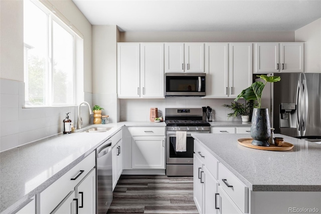 9490 W 14th Ave Unit 3, Lakewood, CO 80215 - kitchen with appliances with stainless steel finishes, a sink, white cabinets, and tasteful backsplash