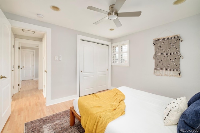 bedroom with a closet, baseboards, light wood-style flooring, and a ceiling fan