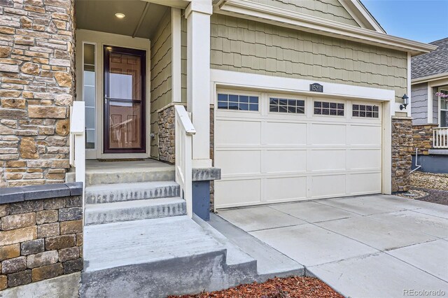 15211 Quince St, Thornton, CO 80602 - view of exterior entry with stone siding, a garage, and concrete driveway