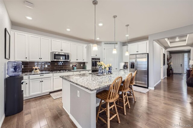 15211 Quince St, Thornton, CO 80602 - kitchen featuring appliances with stainless steel finishes, wood-type flooring, a kitchen island with sink, white cabinets, and recessed lighting