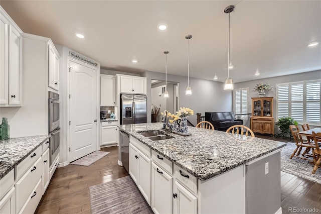 15211 Quince St, Thornton, CO 80602 - kitchen featuring appliances with stainless steel finishes, a sink, an island with sink, dark wood-style floors, and white cabinets
