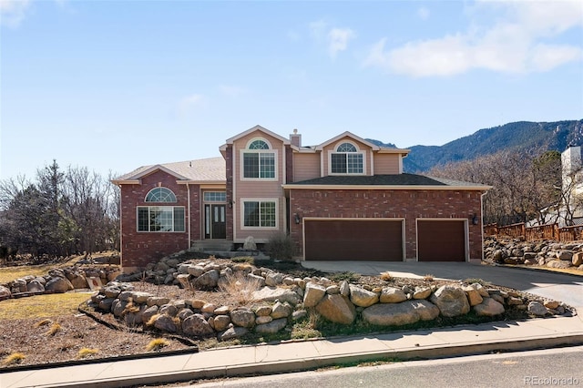 traditional home featuring aphalt driveway, brick siding, a chimney, and an attached garage