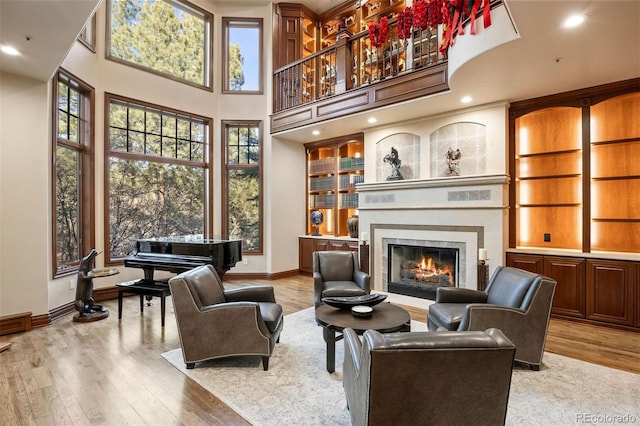 living area featuring a high ceiling, light hardwood / wood-style floors, and built in shelves