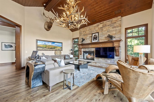 living room featuring a stone fireplace, hardwood / wood-style floors, beamed ceiling, a notable chandelier, and wooden ceiling