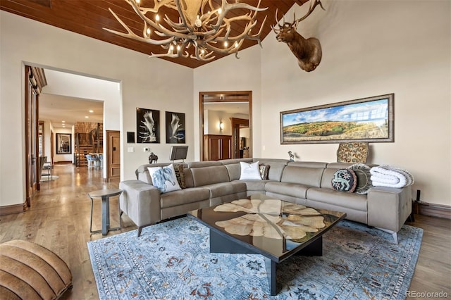 living room featuring a notable chandelier, a towering ceiling, and light wood-type flooring