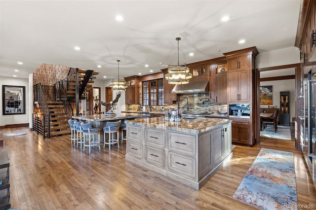 kitchen with pendant lighting, a kitchen bar, light stone countertops, and a kitchen island