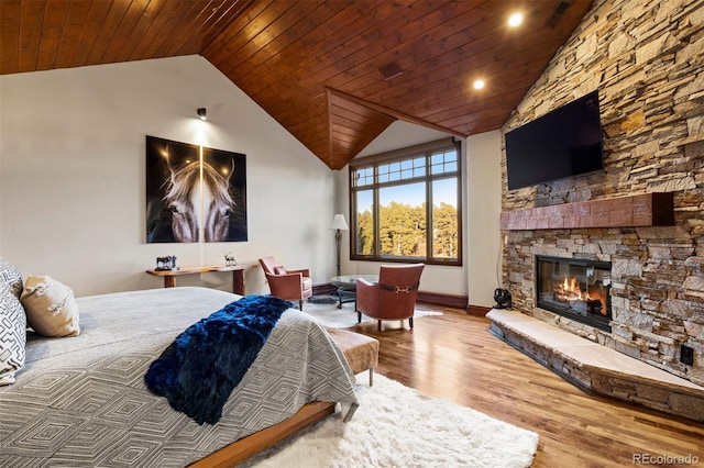 bedroom with wood-type flooring, lofted ceiling, a stone fireplace, and wood ceiling