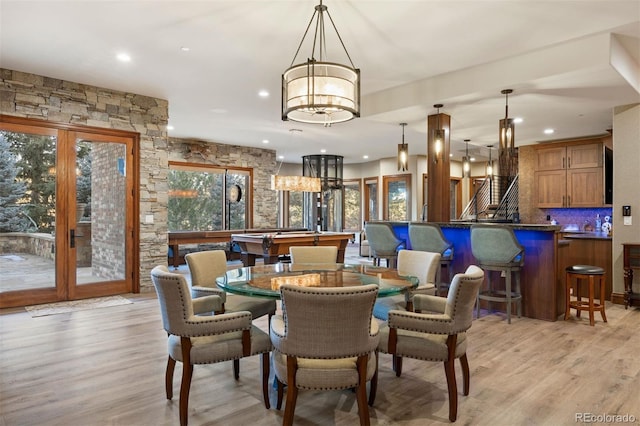 dining room with french doors, indoor bar, and light hardwood / wood-style floors