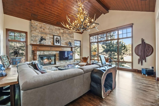 living area featuring a wealth of natural light, beam ceiling, an inviting chandelier, wood ceiling, and a stone fireplace