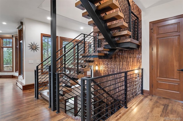 stairway with baseboards, wood finished floors, and recessed lighting