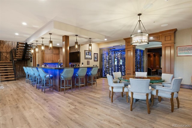 dining area featuring stairs, indoor wet bar, recessed lighting, and light wood-style floors