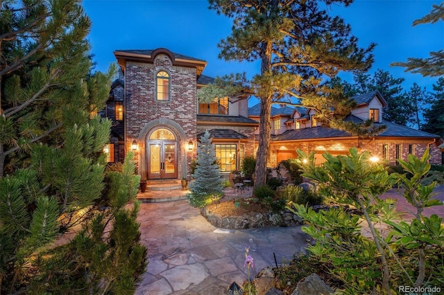 mediterranean / spanish house featuring brick siding and french doors