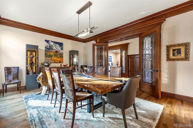 dining space with light wood-style flooring, baseboards, and ornamental molding