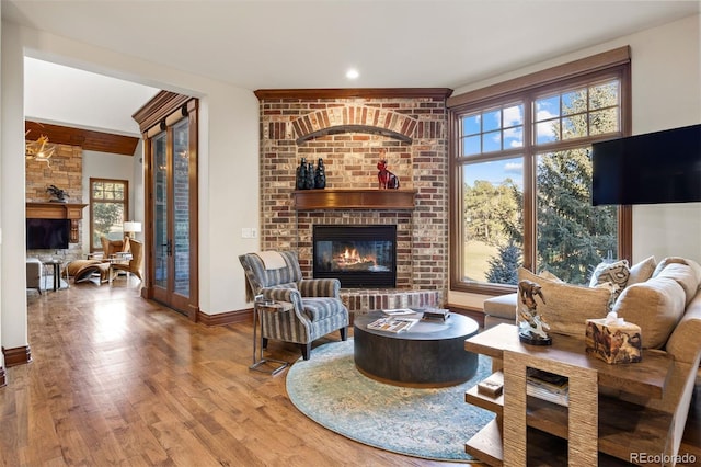 living area with wood finished floors, a brick fireplace, and a healthy amount of sunlight