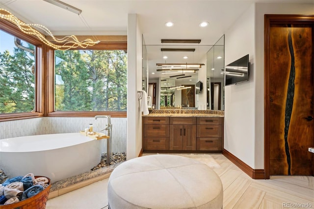 bathroom with vanity, recessed lighting, a freestanding bath, and a healthy amount of sunlight
