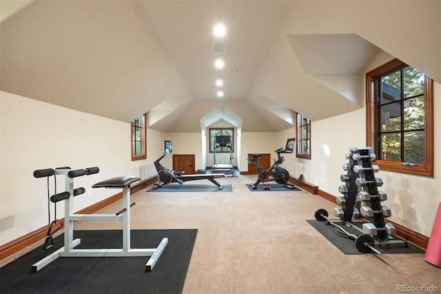 exercise room featuring baseboards, a healthy amount of sunlight, visible vents, and lofted ceiling