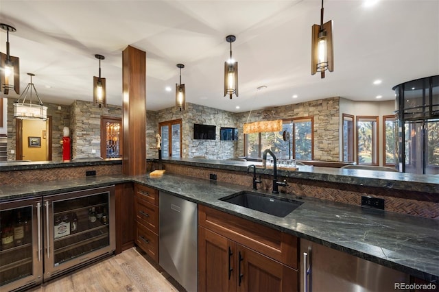 bar with a sink, beverage cooler, light wood-style floors, dishwasher, and decorative light fixtures