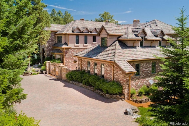 tudor-style house with a chimney, brick siding, and stucco siding