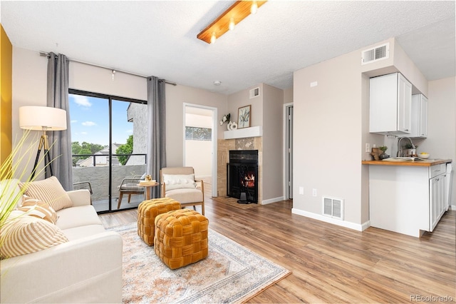 1820 Newland Ct Unit 310, Lakewood, CO 80214 - living area featuring light wood-style flooring, a tiled fireplace, and baseboards