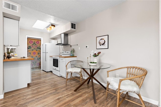 1820 Newland Ct Unit 310, Lakewood, CO 80214 - kitchen with white appliances, wall chimney range hood, wooden counters, white cabinets, and a textured ceiling