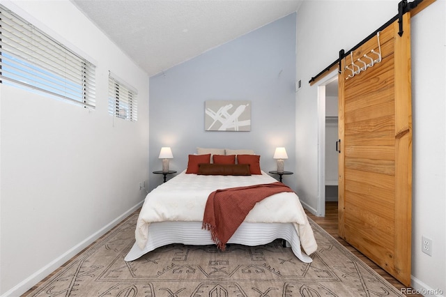1820 Newland Ct Unit 310, Lakewood, CO 80214 - bedroom with a barn door, vaulted ceiling, baseboards, and light wood finished floors