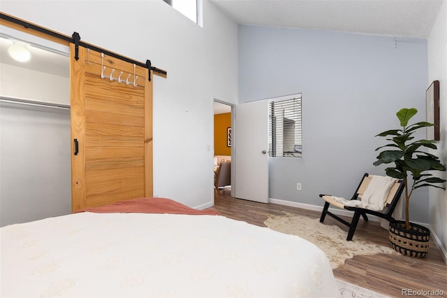 1820 Newland Ct Unit 310, Lakewood, CO 80214 - bedroom featuring a barn door, wood finished floors, baseboards, and high vaulted ceiling