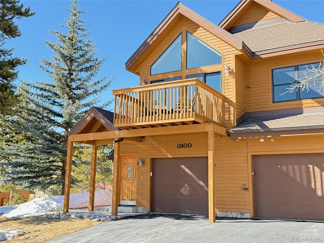 rustic home with a garage, a balcony, and a shingled roof