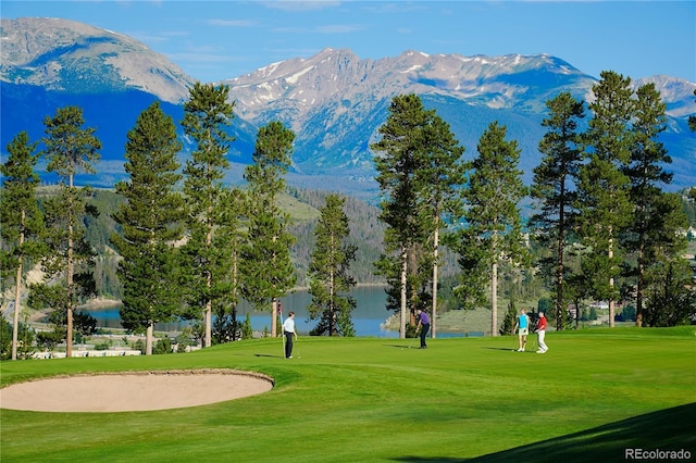 view of community featuring view of golf course, a yard, and a water and mountain view