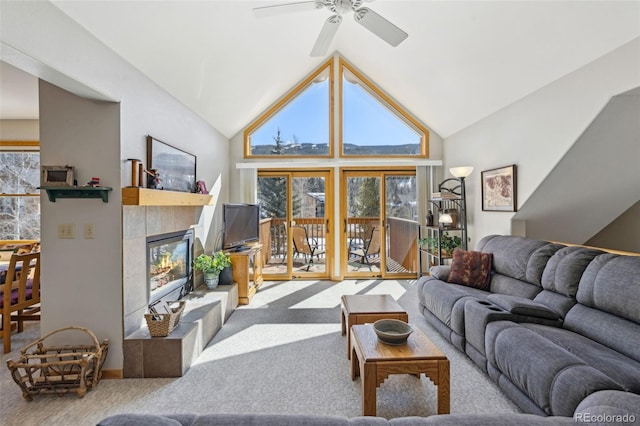 living area featuring carpet flooring, a tile fireplace, high vaulted ceiling, and ceiling fan